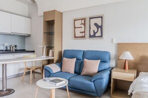 A modern living room with a blue sofa, a small round table, and a nightstand with a lamp. - Blueground | Jingxin Village, pool, nr Taipei 101 (TPE-14) (Taipei)