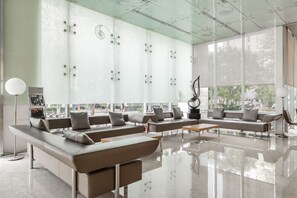Espaço de convívio moderno com sofás de couro, uma mesa de centro e uma escultura.