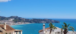 Une ville côtière caractérisée par une colline imposante, une mer d’un bleu limpide et une vue imprenable sur l’océan.