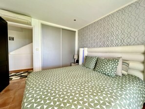 Une chambre à coucher avec une couvre-lit à motifs, une tête de lit et un mur décoré d’un motif.