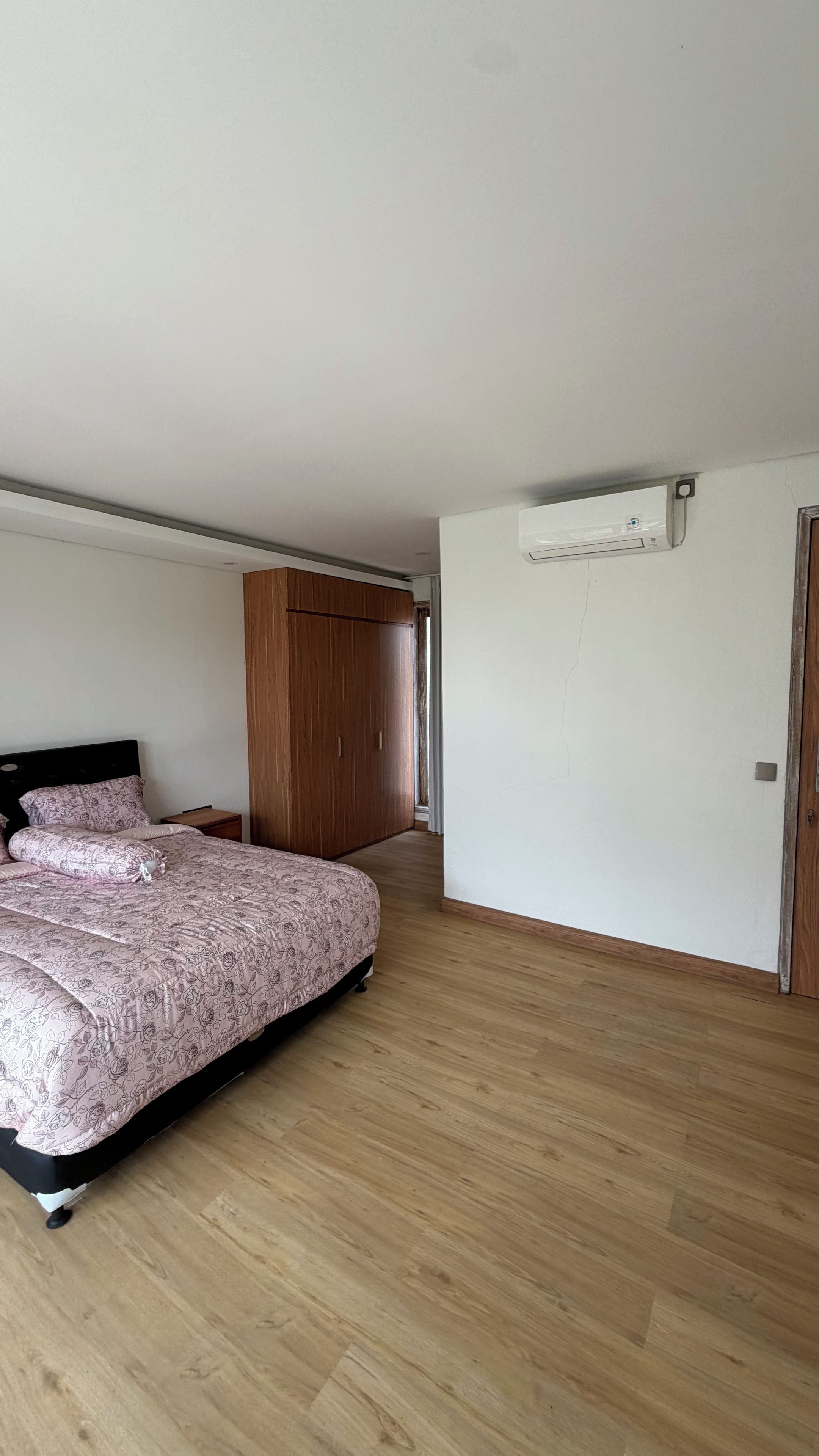 Un dormitorio con cama, armario y equipo de aire acondicionado.
