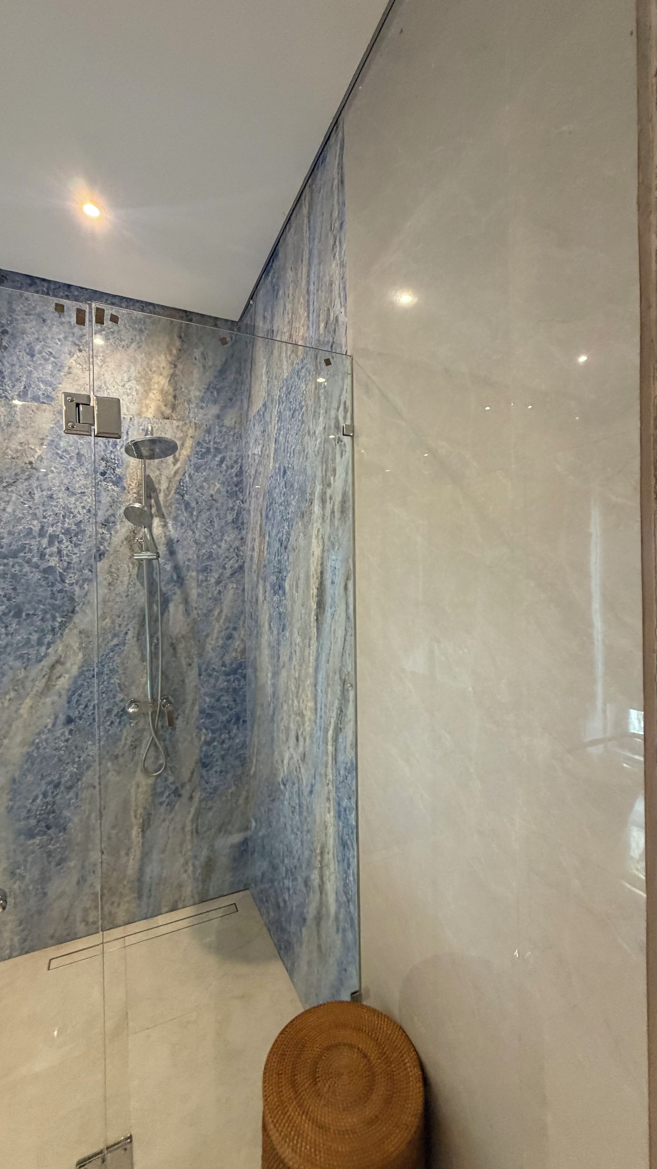 A bathroom with a shower, a toilet, and a wall with a marble-like texture.
