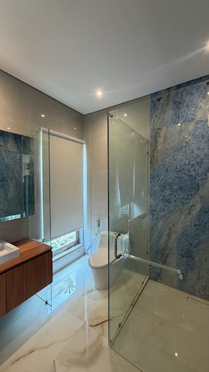 Un baño moderno con cabina de ducha de vidrio, inodoro y tocador con espejo.