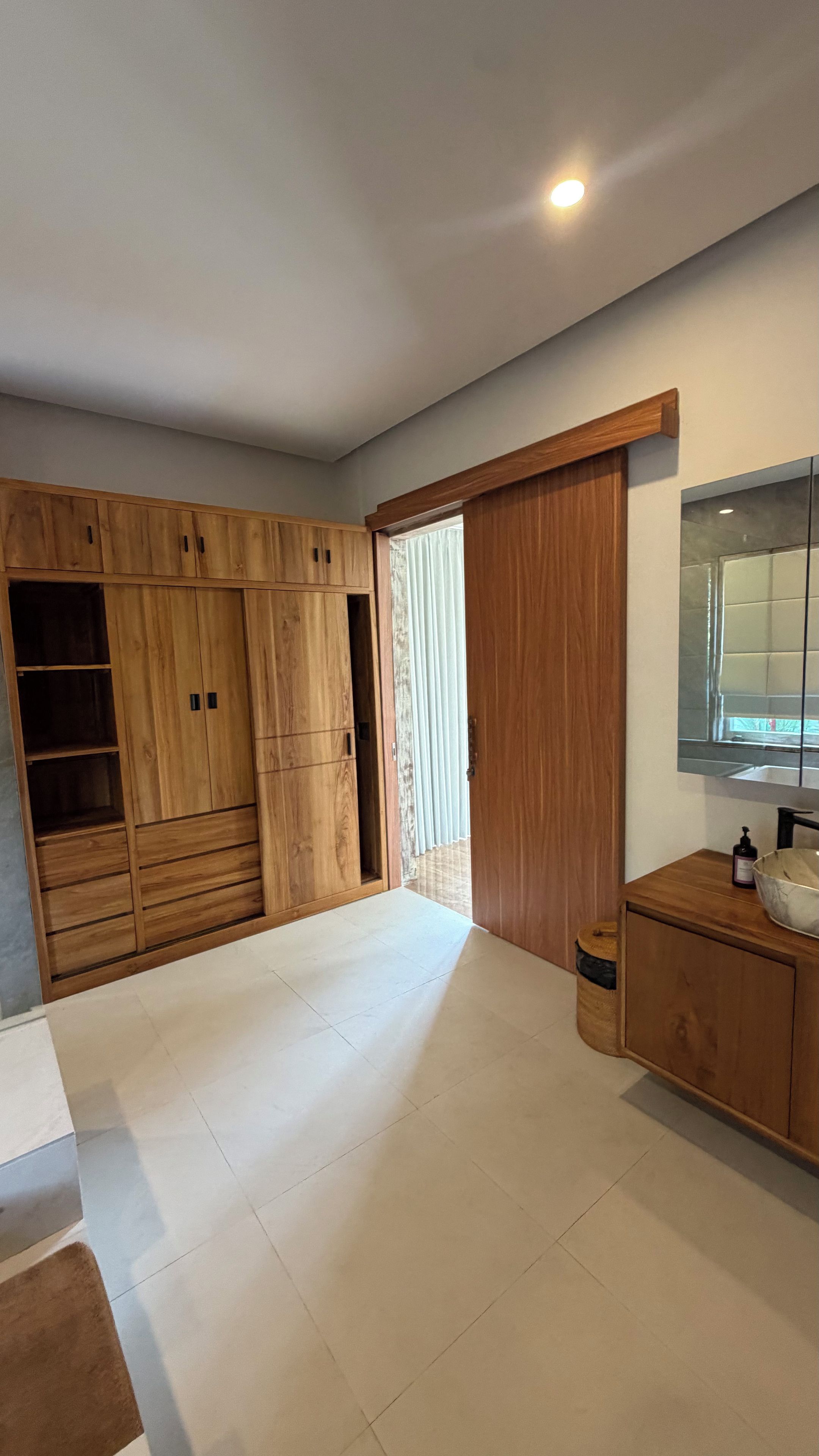 Un baño moderno con un tocador de madera, un espejo y un armario grande.