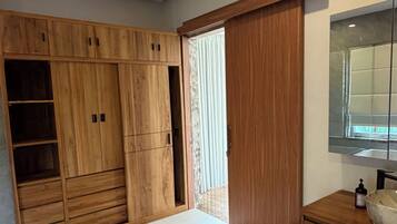 Un baño moderno con un tocador de madera, un espejo y un armario grande.
