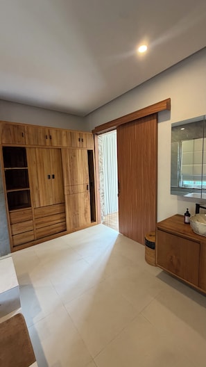 Un baño moderno con un tocador de madera, un espejo y un armario grande.