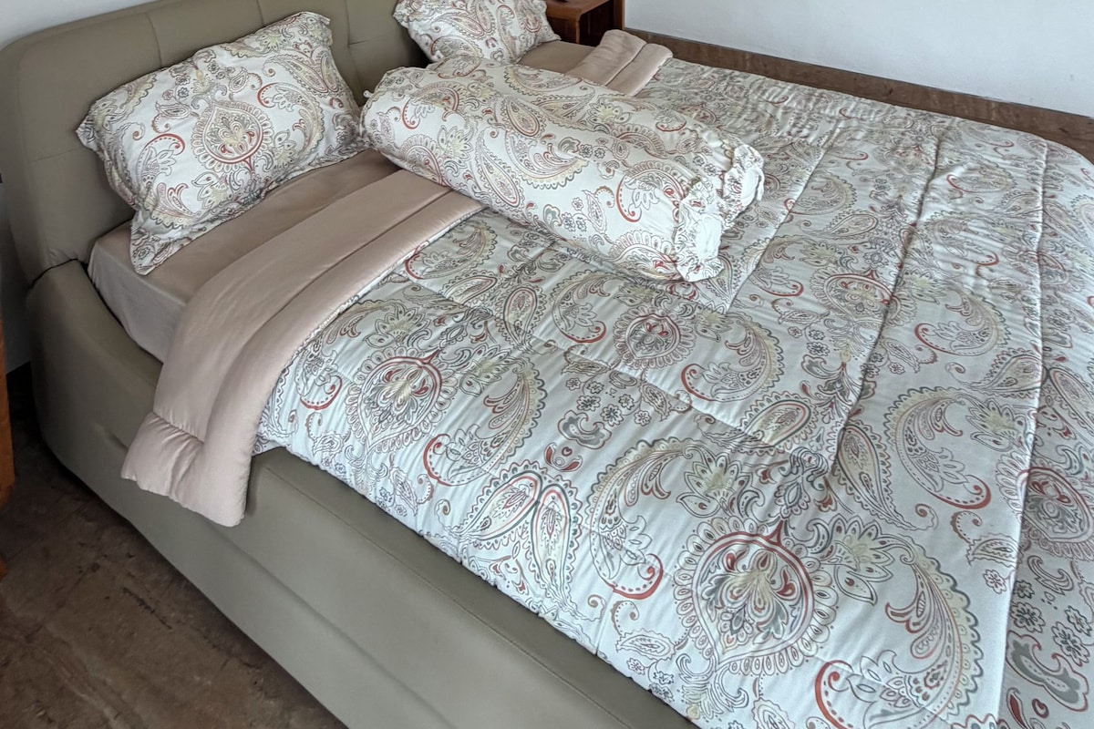 Un dormitorio con cama, mesita de noche y unidad de aire acondicionado.