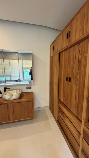 Un baño moderno con tocador de madera, un espejo grande y lavamanos de mármol.