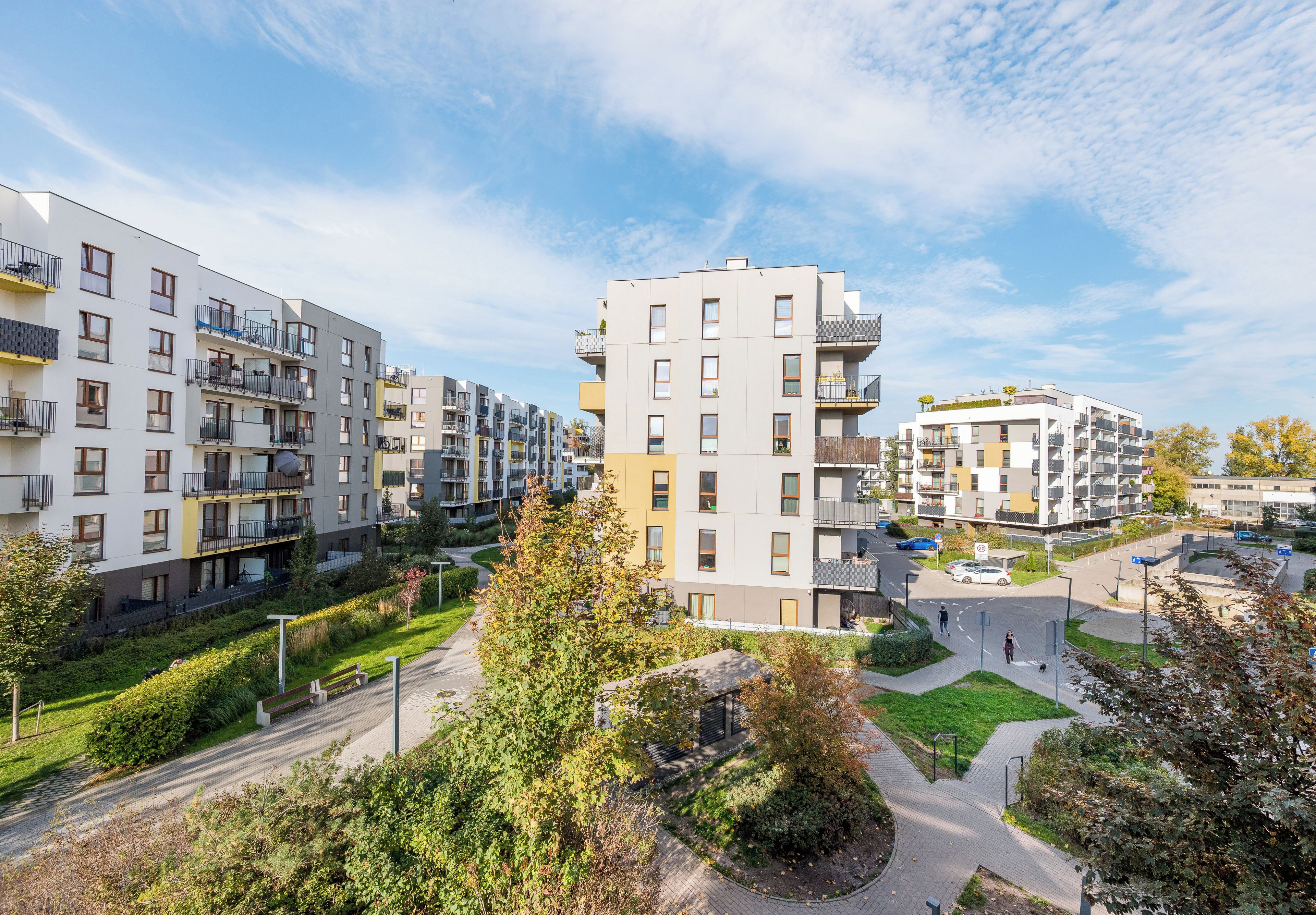 A residential building with multiple balconies, a central courtyard, and a surrounding green space.