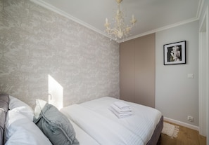 A bedroom with a bed, a chandelier, a wardrobe, and a framed picture on the wall. - Krochmalna Glamour Apartment (Warszawa)