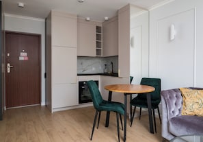 A compact living space with a kitchenette, a dining area with two chairs, and a sofa. - Krochmalna Glamour Apartment (Warszawa)