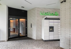 Een moderne gevel met glazen deur, een bakstenen muur en een neonreclame.