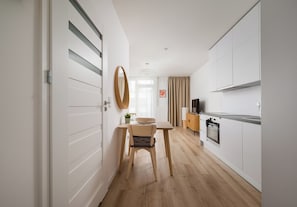 A modern kitchen with a dining area, wooden flooring, and a large mirror. - Browary Warszawskie Velvet Studio (Warszawa)