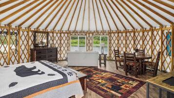 A yurt interior with a bed, a dining table, and chairs.