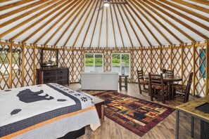 A yurt interior with a bed, a dining table, and chairs.