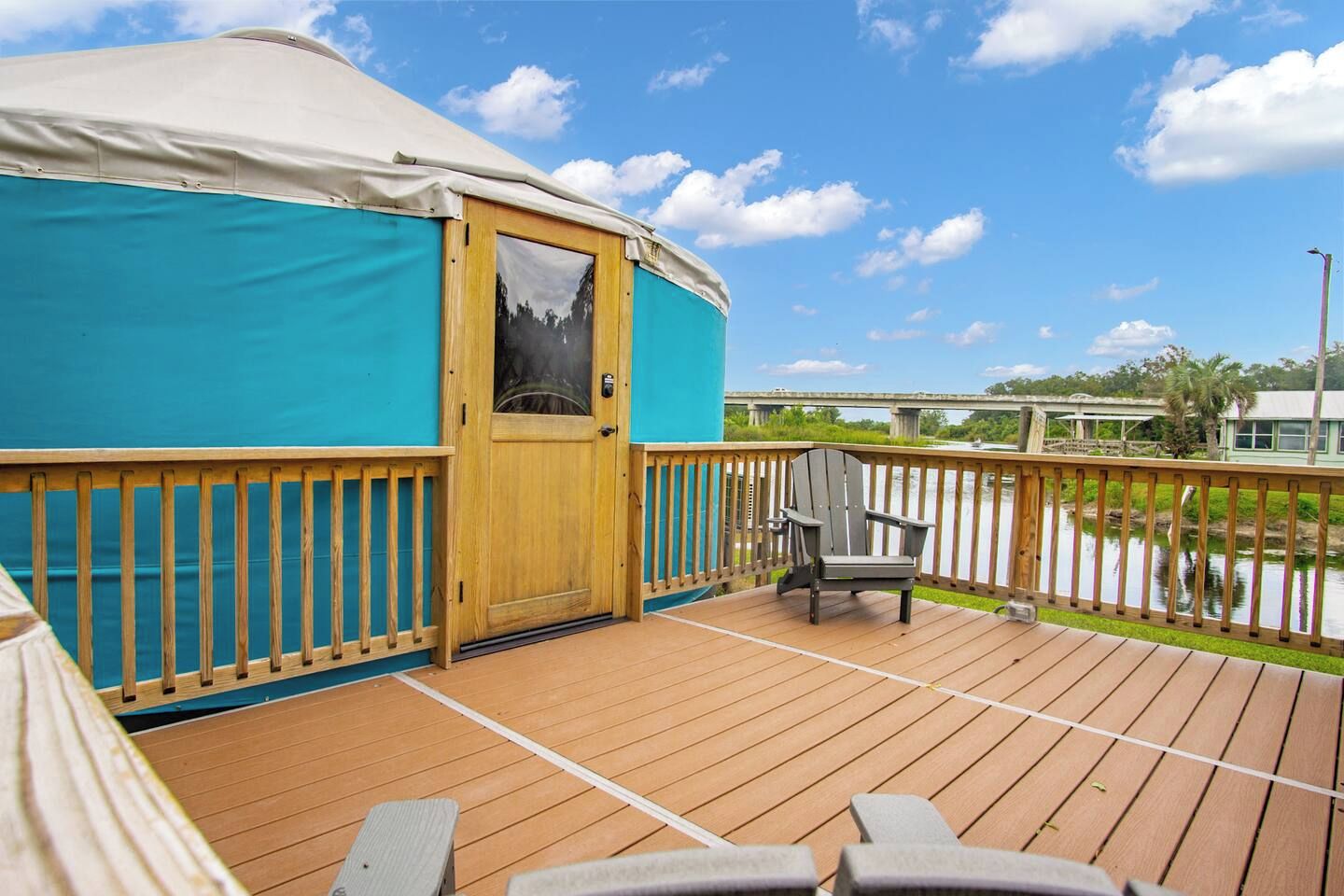 Una terraza de madera con un espacio cubierto, una puerta y una silla.