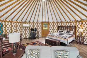 Eine Jurte mit Bett, Schreibtisch, Lampe und Sofa.