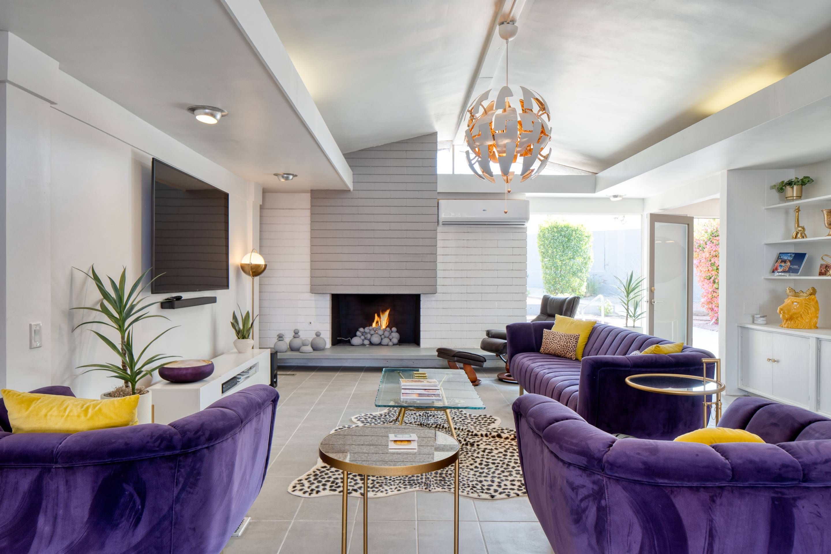 A modern living room with a fireplace, sofas, and a television.