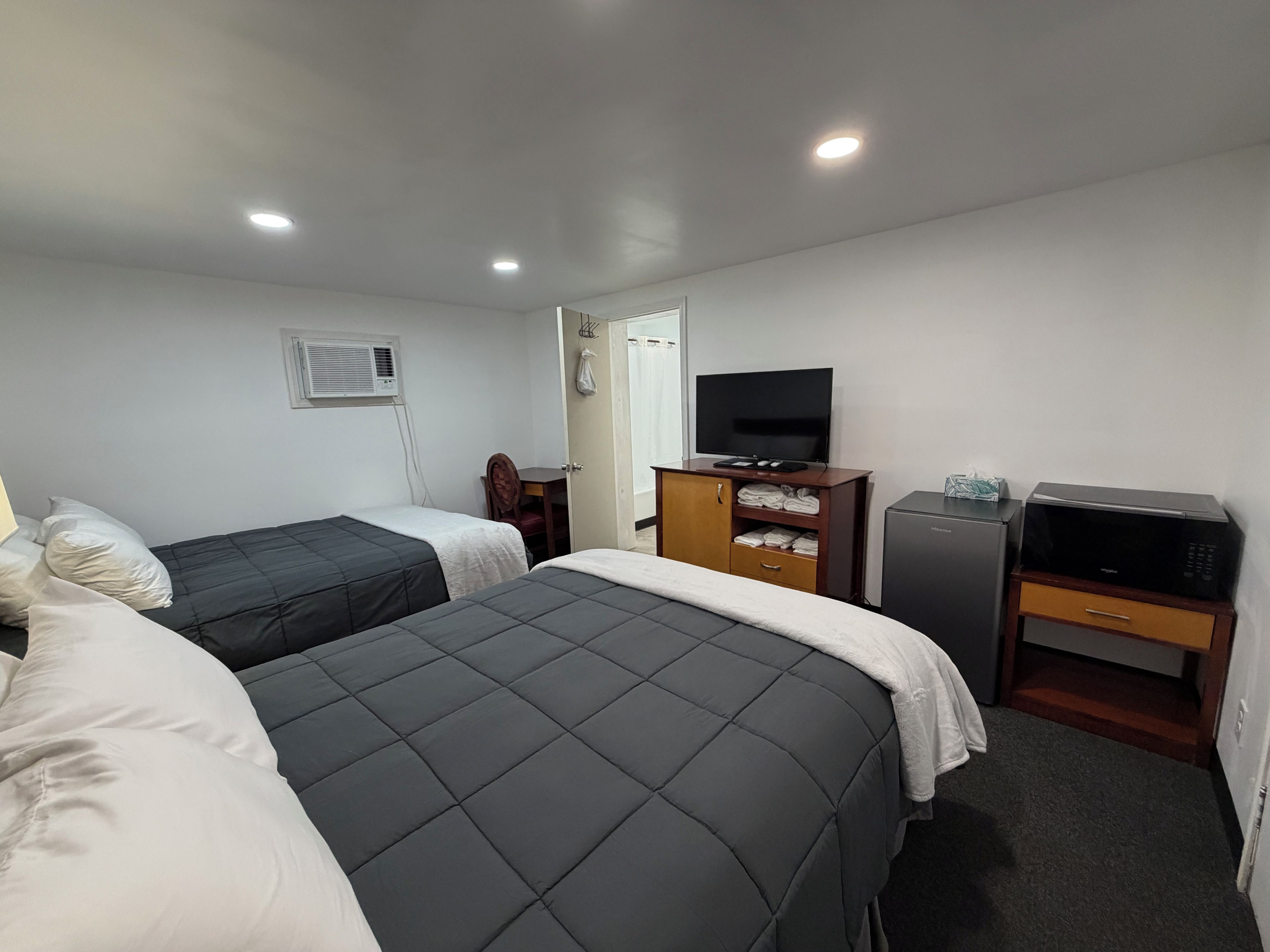 Habitació d'hotel amb dos llits, televisió, barra minibar i escriptori.