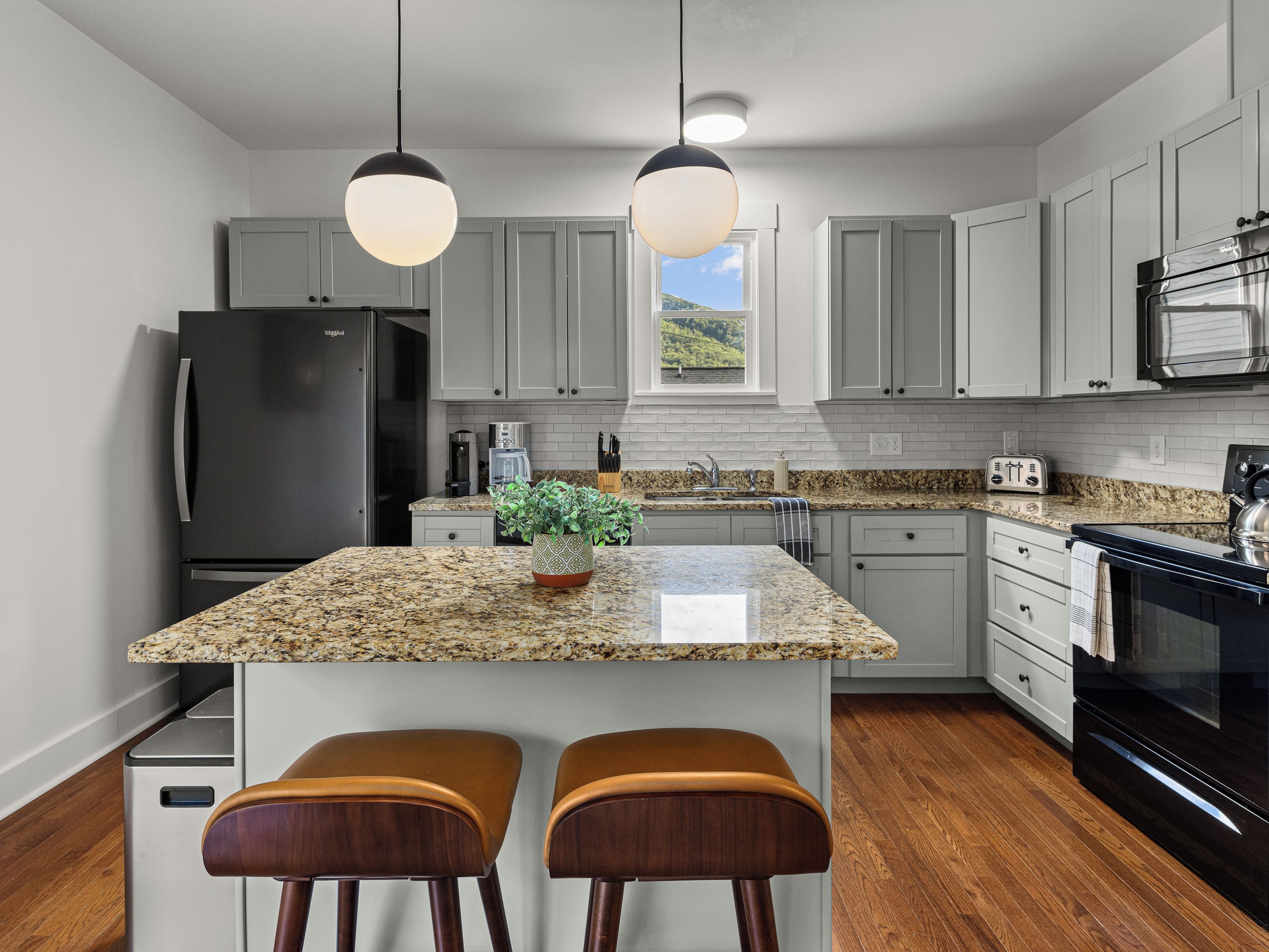 A kitchen with a granite countertop, stainless steel appliances, and a window with a view.