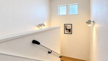 A staircase with a handrail, a light fixture, and a framed picture on the wall.