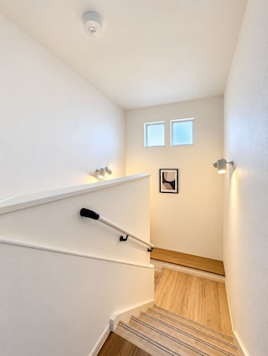 Eine Treppe mit Handlauf, einer Lampe und einem gerahmten Bild an der Wand.