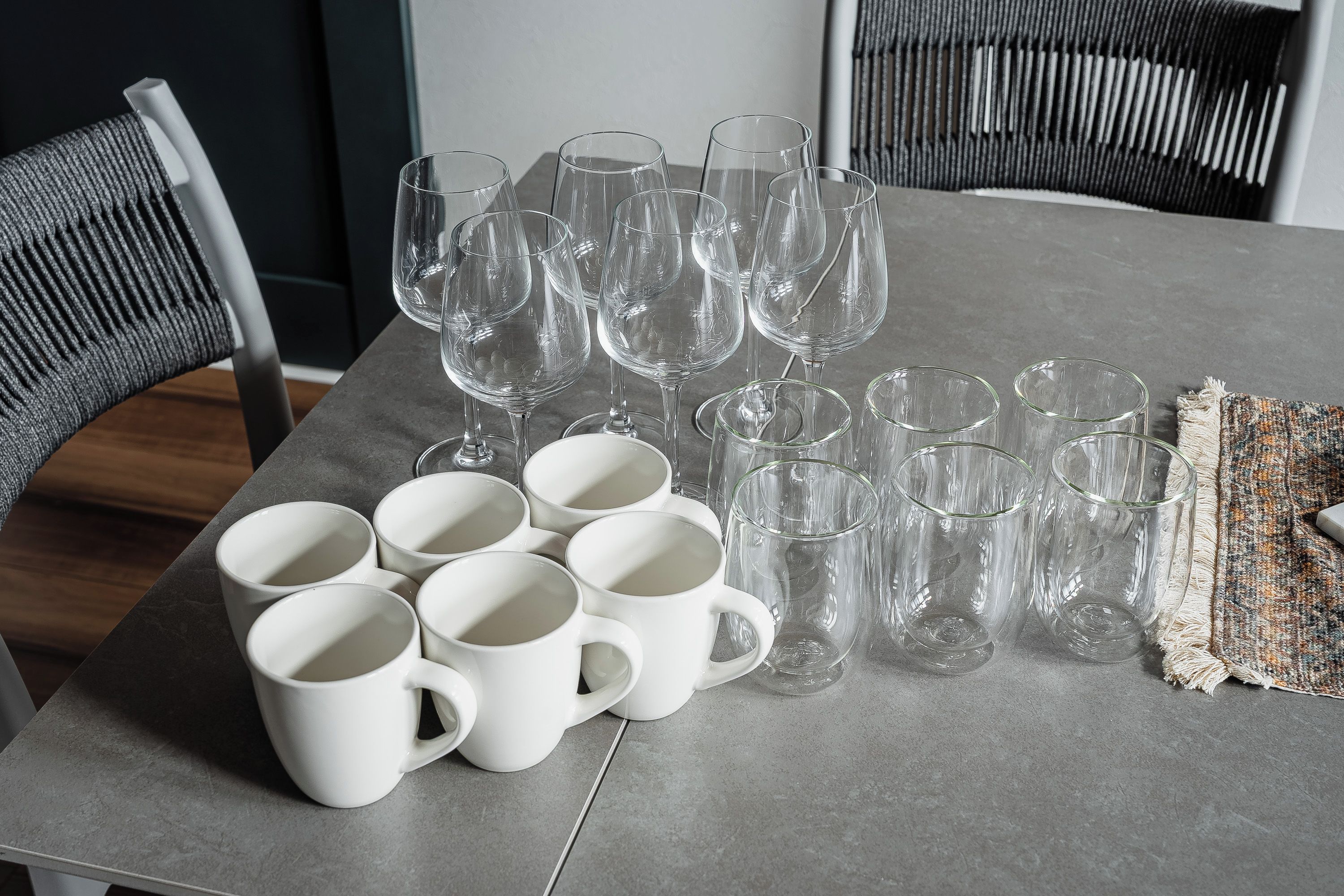 A table with several white mugs and clear glassware, likely for a gathering or event.