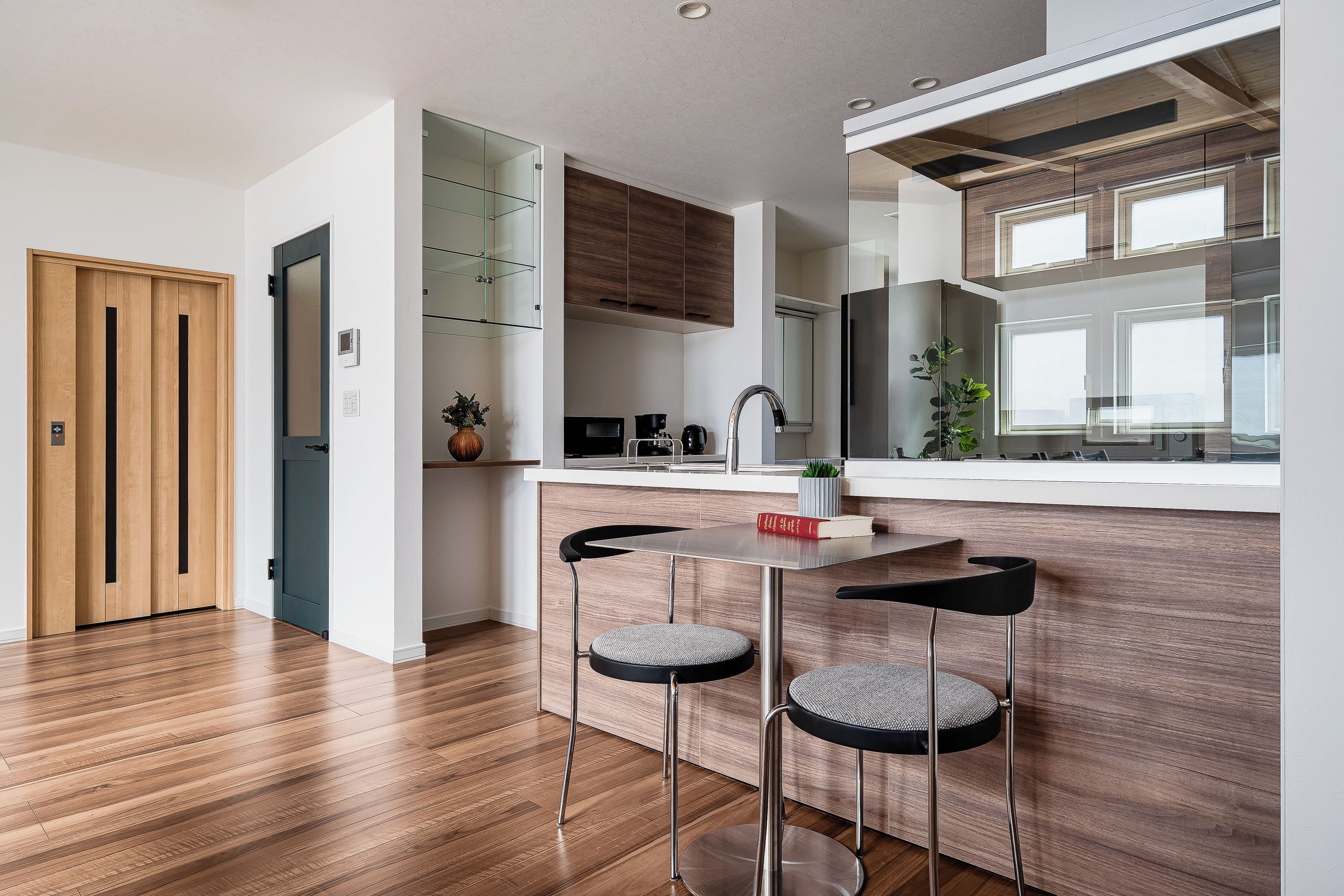 A modern kitchen with wooden cabinets, a built-in oven, and a window overlooking the room.