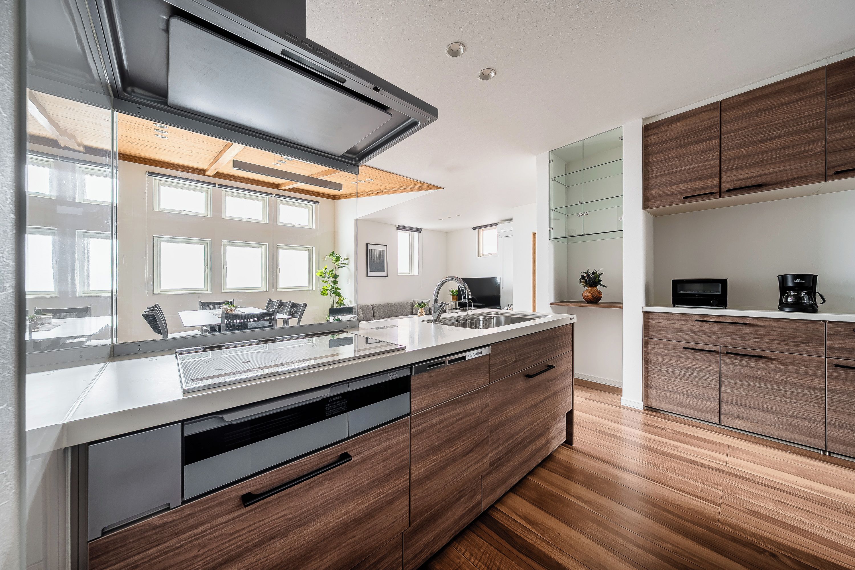 A modern kitchen with a large island, wooden cabinets, and a built-in oven.