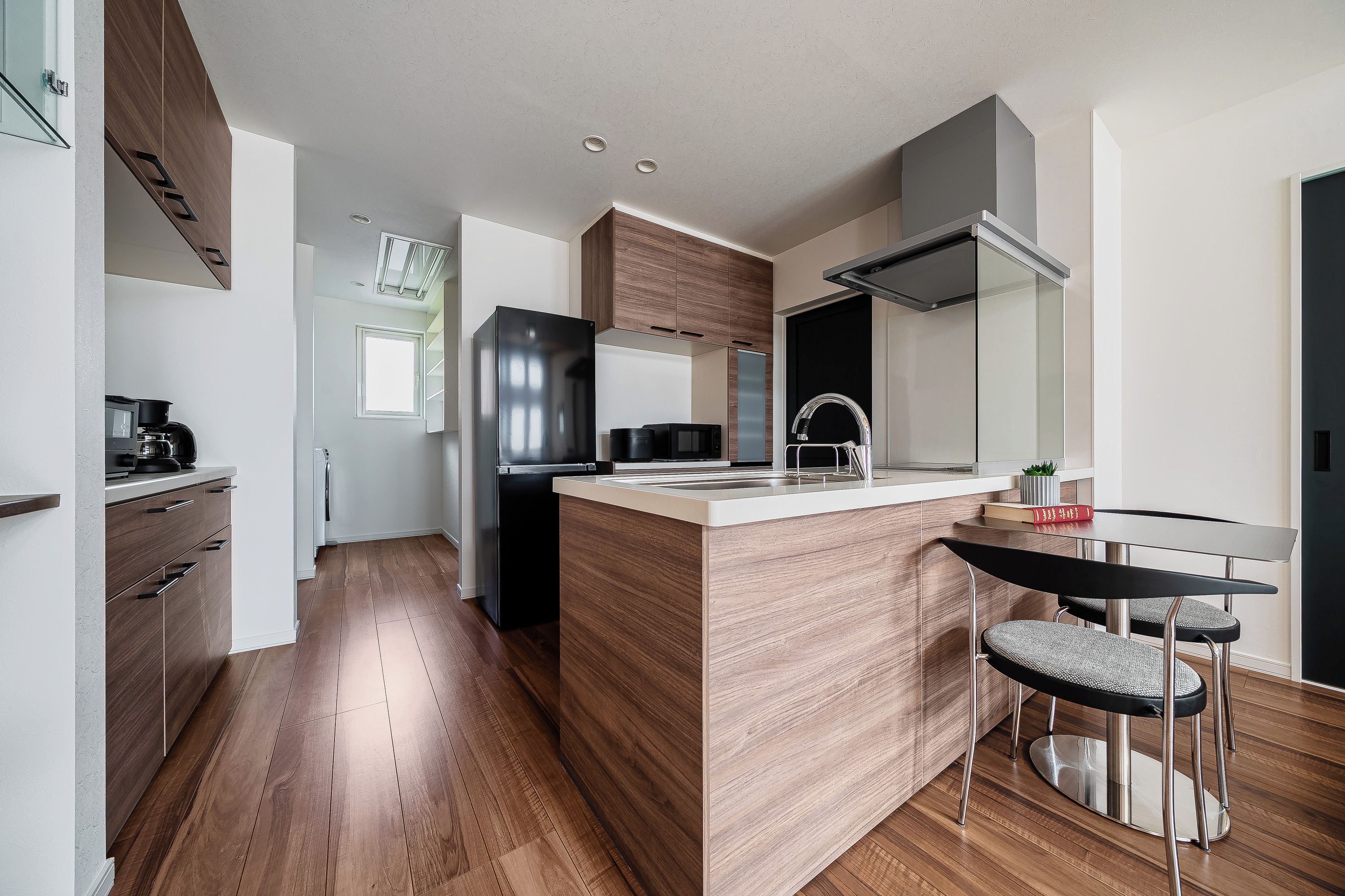 A modern kitchen with a central island, stainless steel appliances, and a dining area with a chair and table.