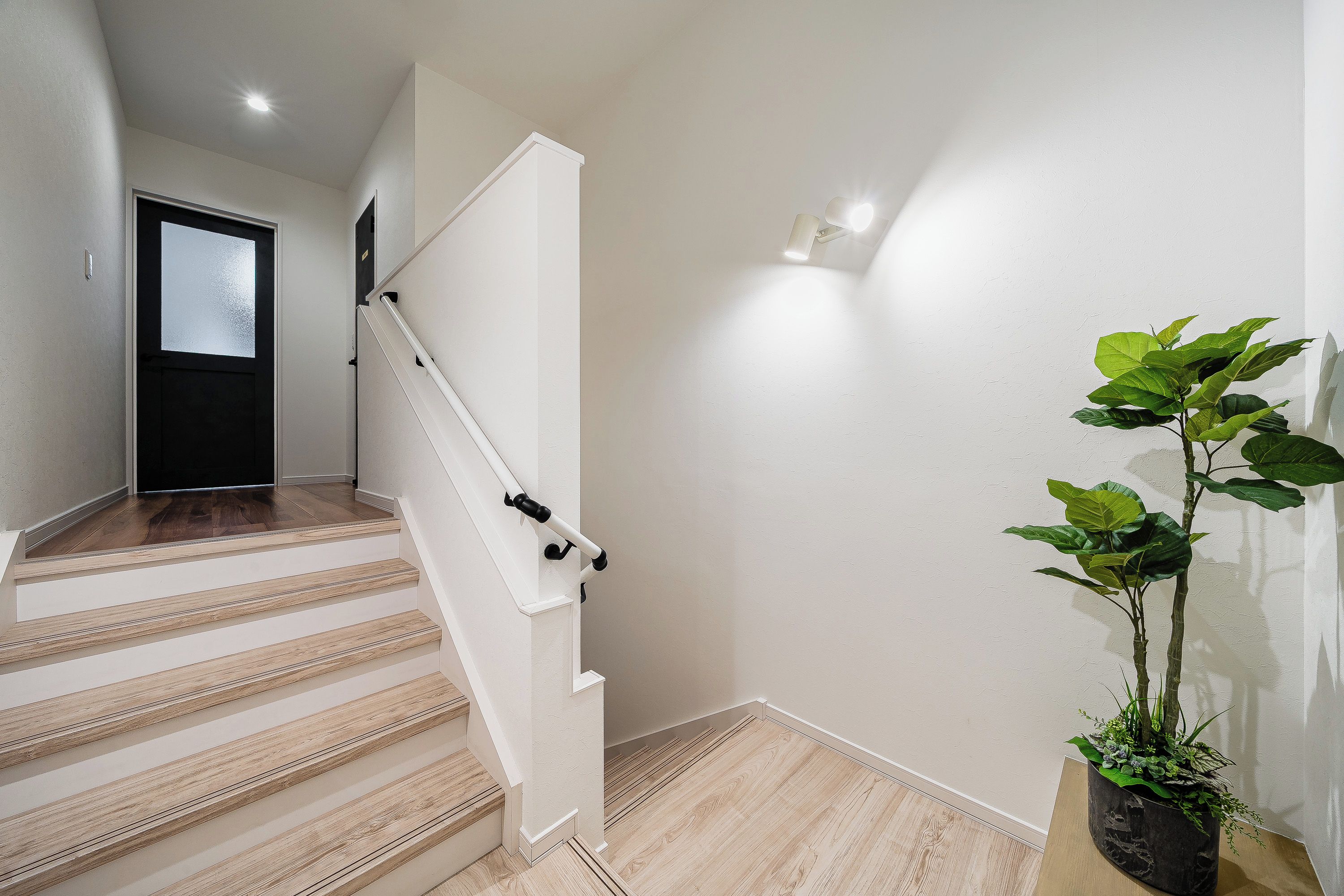 A staircase with wooden steps and white handrails, leading to a door with frosted glass panels.