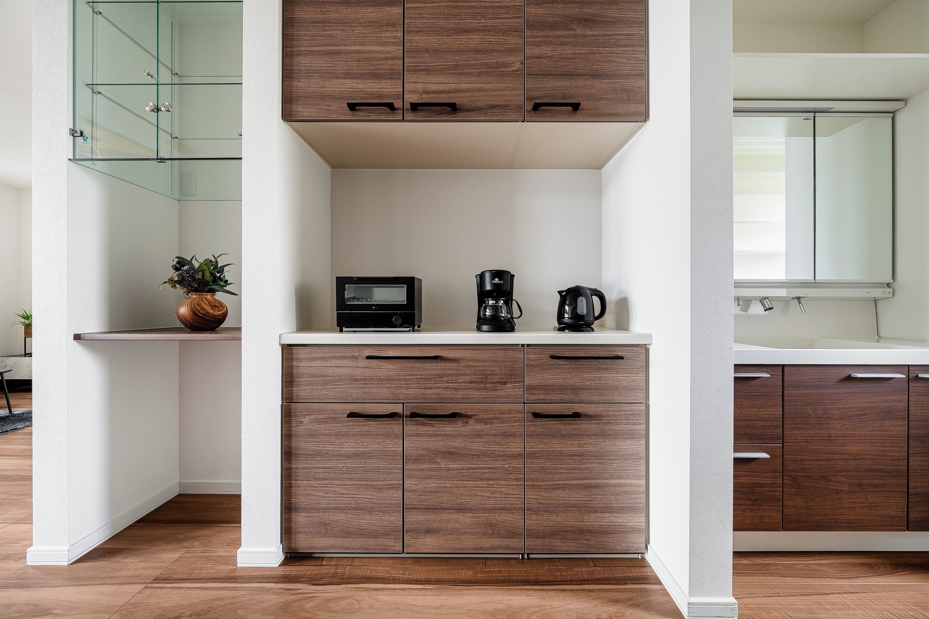 A modern kitchen with wooden cabinets, a microwave, a coffee maker, and a glass shower enclosure.