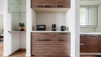 A modern kitchen with wooden cabinets, a microwave, a coffee maker, and a glass shower enclosure.