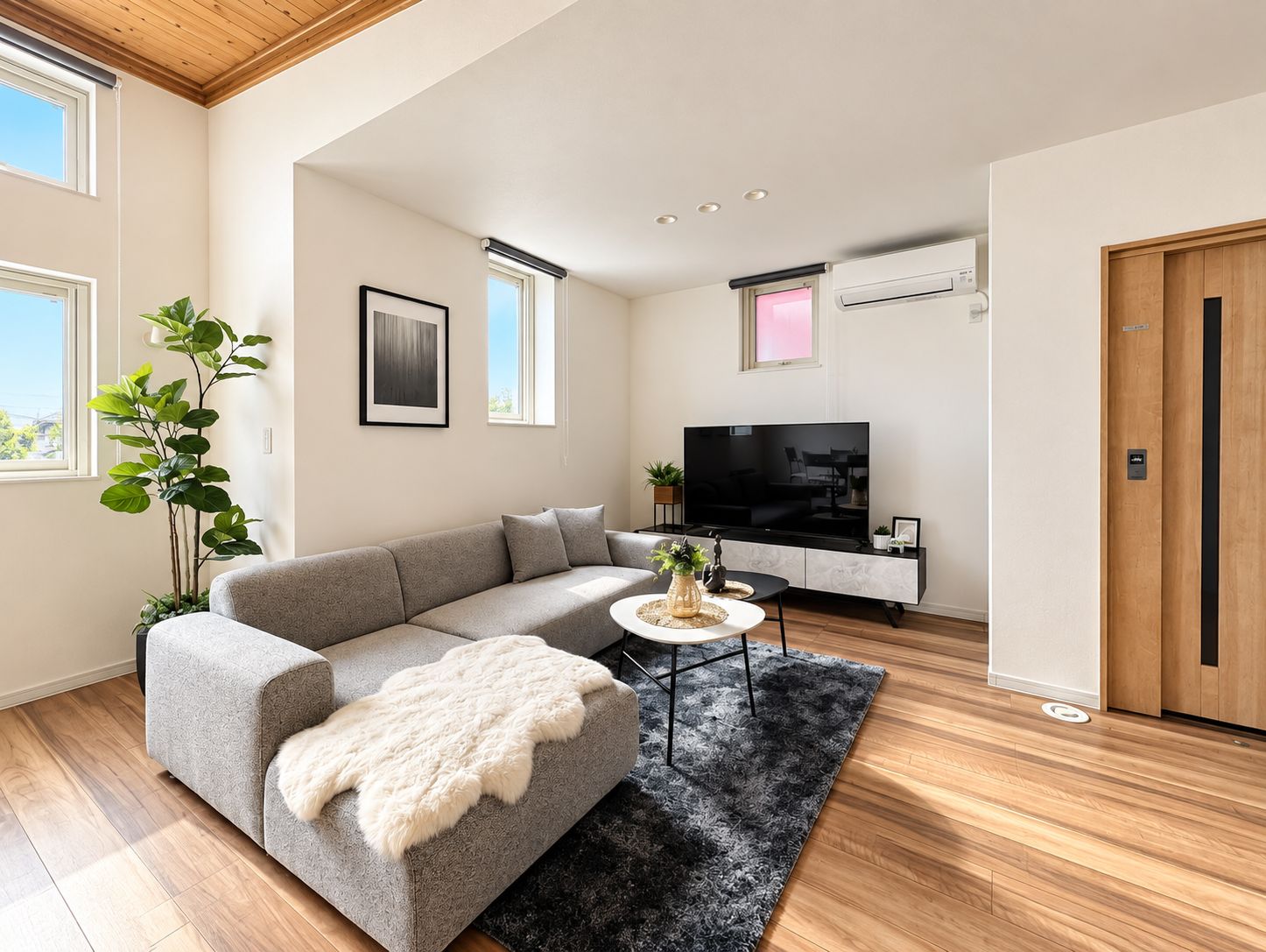 A modern living room with a grey sofa, a round coffee table, and a large flat-screen TV.