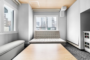 A modern room with a large window, a cushioned bench, a wooden table, and a white cabinet with labels. - Miipo (Sapporo)