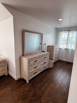 A room with a large wooden dresser, a mirror, and a window with curtains.