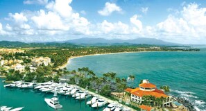 A coastal property with a marina, a large building with a red roof, and a view of the beach and mountains in the distance. - Casa Magia - 3BR Modern Home Near San Juan (Guaynabo)
