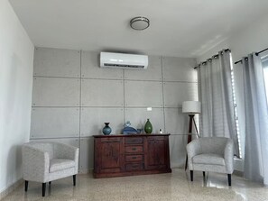 A room with a tiled wall, a wooden cabinet, two armchairs, and a floor lamp. - Casa Magia - 3BR Modern Home Near San Juan (Guaynabo)