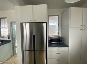 A kitchen with a stainless steel refrigerator, a microwave, and white cabinetry. - Casa Magia - 3BR Modern Home Near San Juan (Guaynabo)