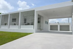 A modern building with large windows, a flat roof, and a paved area in front. - Casa Magia - 3BR Modern Home Near San Juan (Guaynabo)