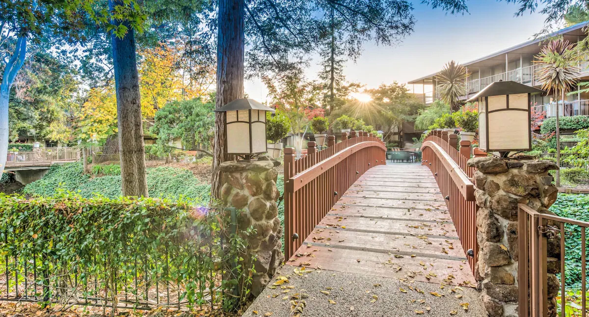 A stone bridge with metal railings leading to a building with a balcony.