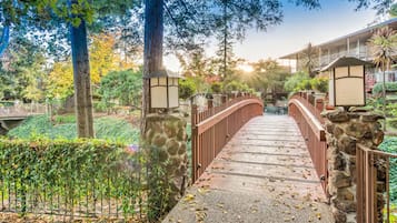 A stone bridge with metal railings leading to a building with a balcony.