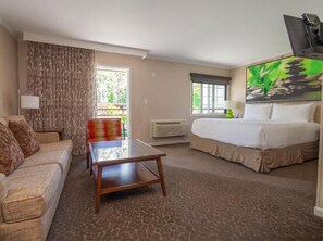 Una habitación de hotel con cama, sofá, mesa, ventana y un cuadro en la pared.