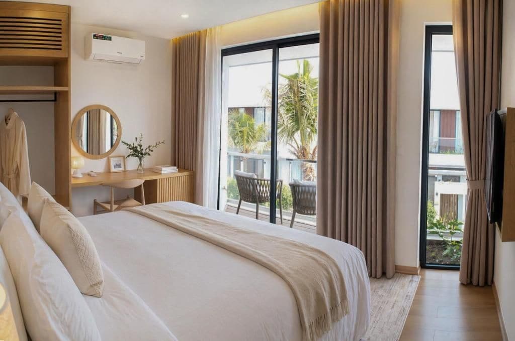 Habitación de hotel con una cama grande, un escritorio con espejo y vistas al exterior a través de una puerta corrediza de vidrio.