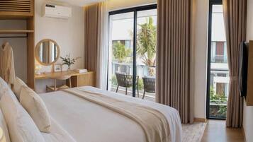 Habitación de hotel con una cama grande, un escritorio con espejo y vistas al exterior a través de una puerta corrediza de vidrio.