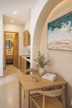 A dining area with a wooden table, chairs, a vase with greenery, and a painting on the wall. - Sea La Vie Beachfront Villa - Long Beach Phu Quoc (Xa Duong To)