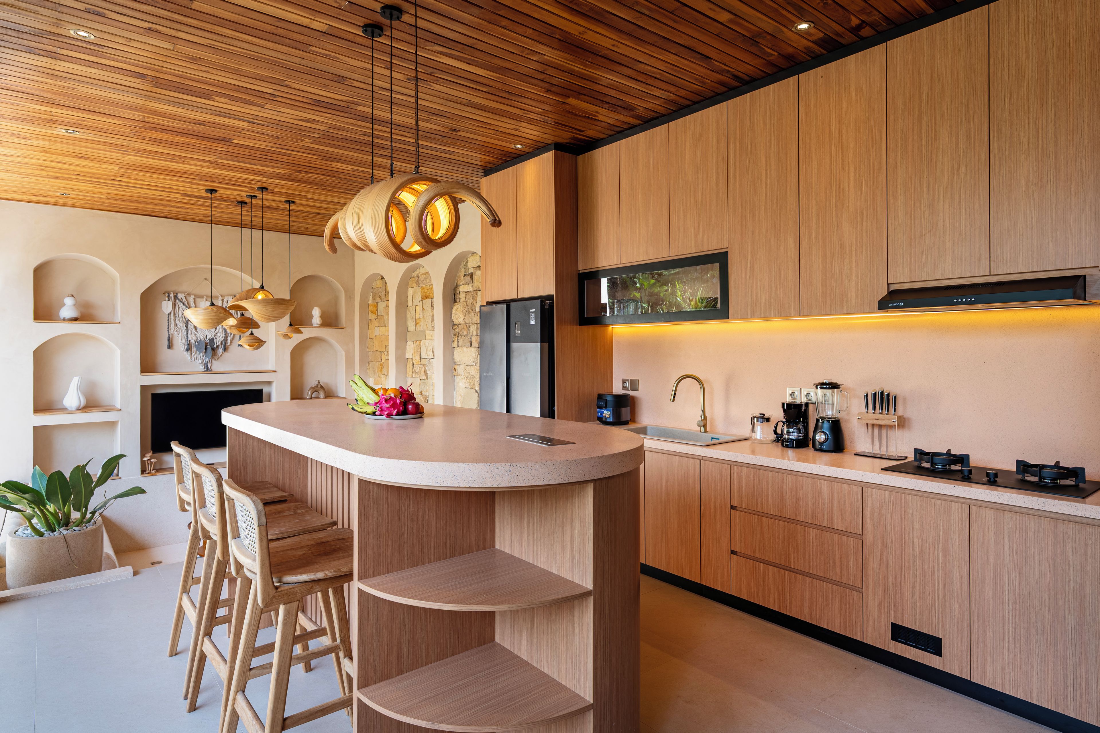 A modern kitchen with wooden cabinetry, a central island, bar stools, and a built-in stove.