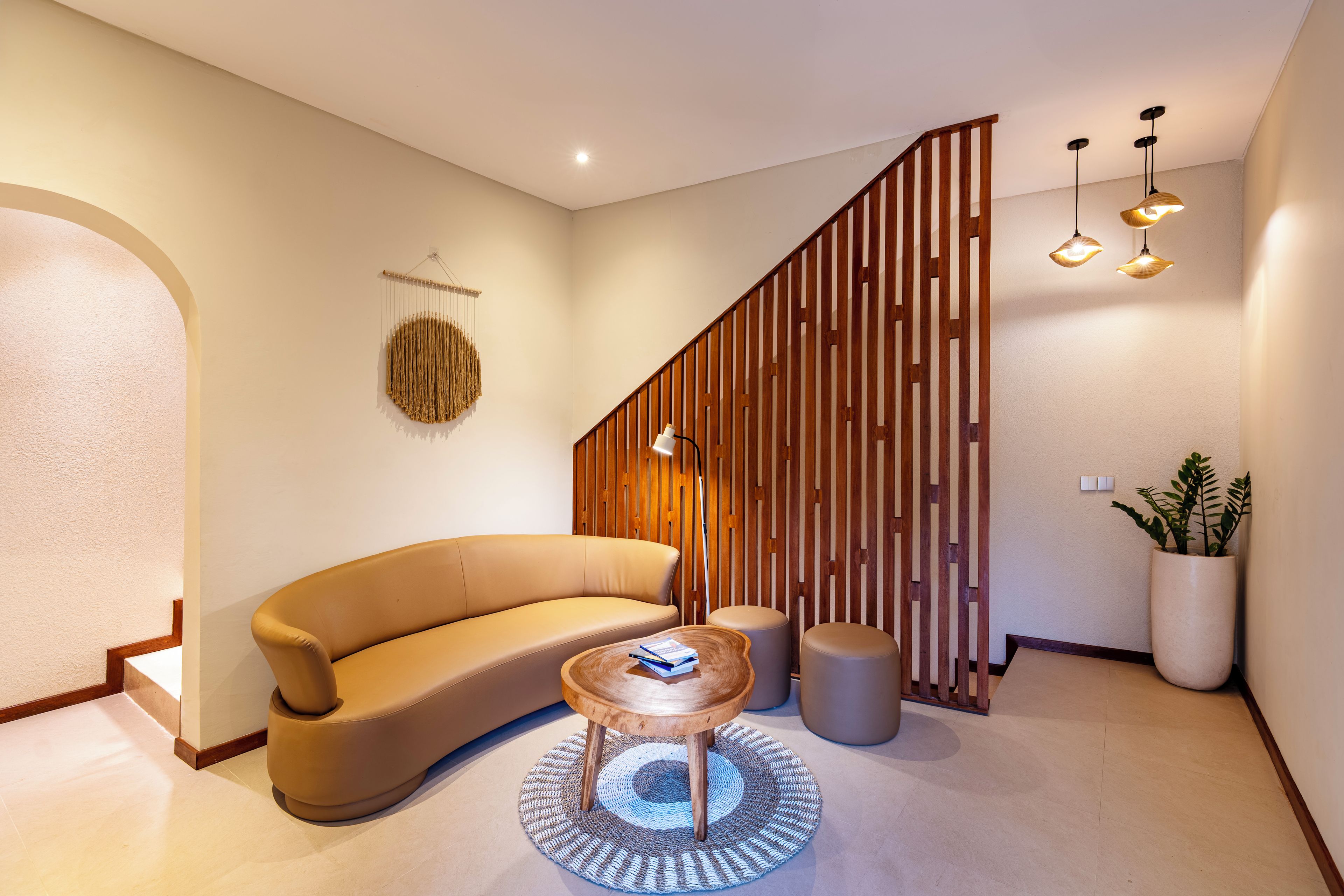 A modern interior with a curved sofa, a small wooden coffee table, and a potted plant.