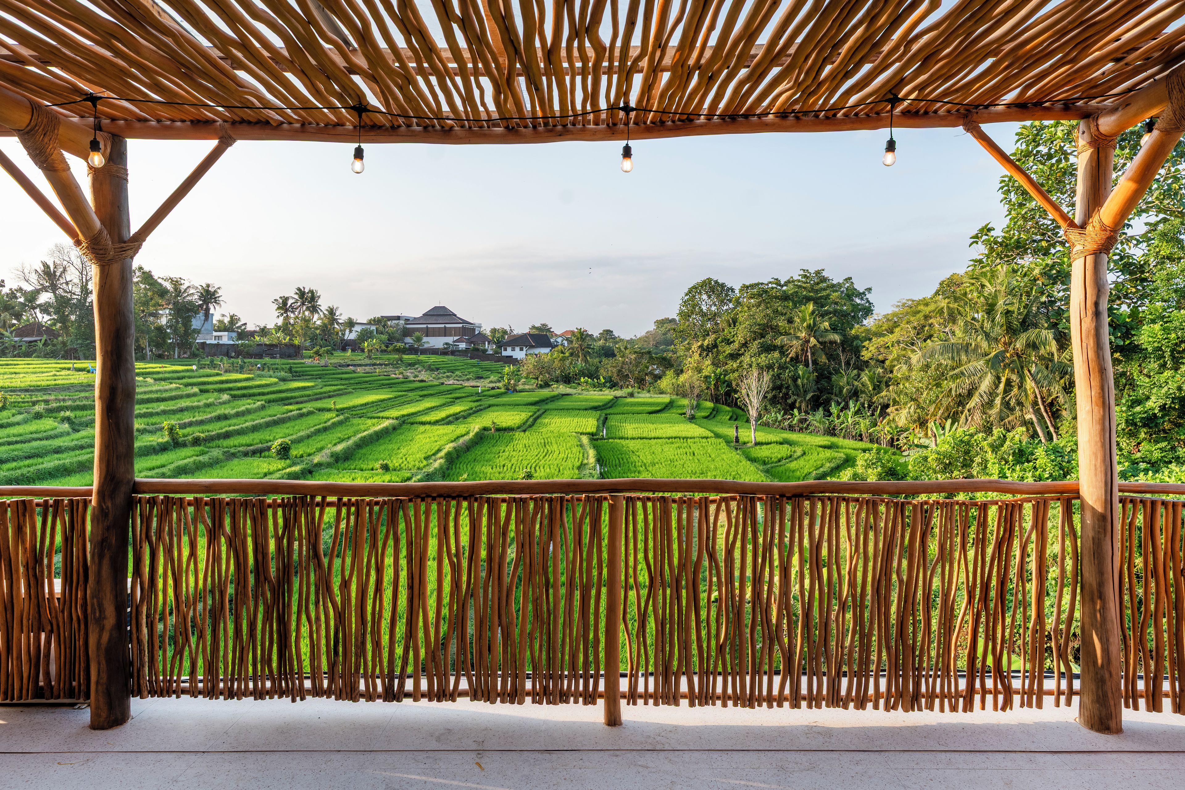 Una pérgola de madera con vistas a campos en terrazas y edificios a lo lejos.