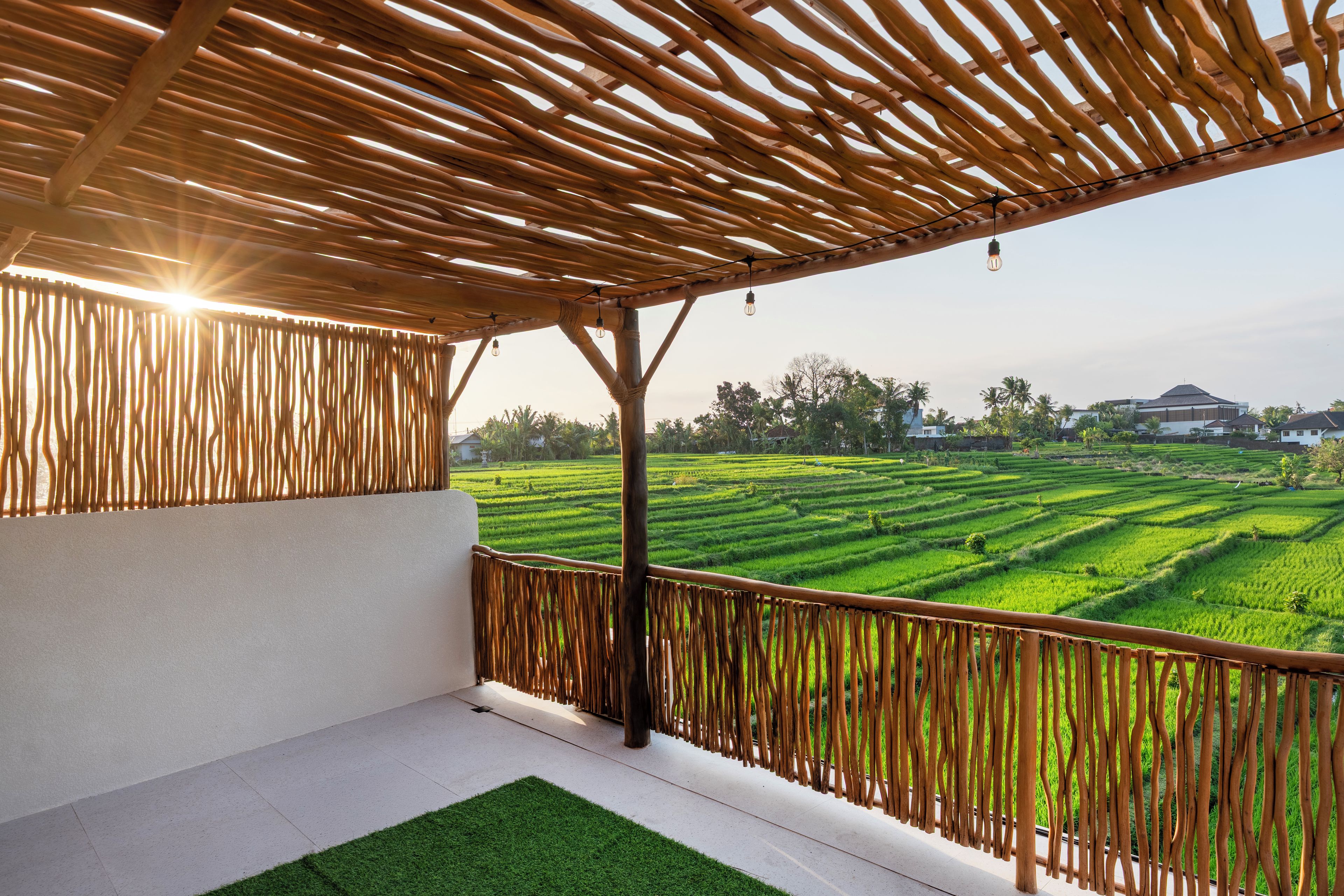 A covered balcony with a view of terraced fields.